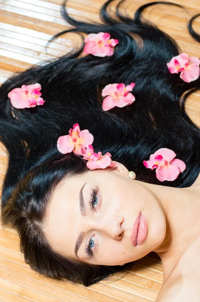 Bella ragazza viso e fiori rosa, pelle e labbra perfette — Foto Stock