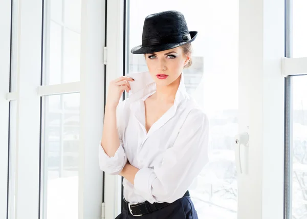 Young business woman wearing man's shirt, hat in office — Stock Photo, Image