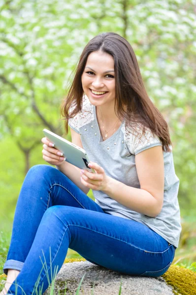 Unga glada leende kvinna som arbetar på pda tablet pc gröna utomhus — Stockfoto