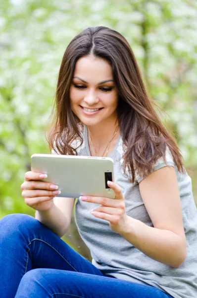 Unga glada leende kvinna som arbetar på pda tablet pc gröna utomhus — Stockfoto
