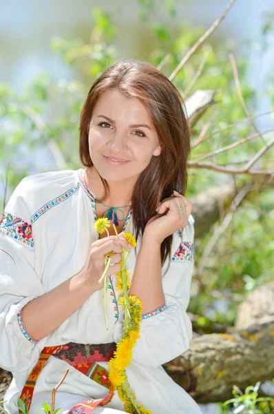 Glad ung i traditionella ukrainska klä gör blomslinga — Stockfoto