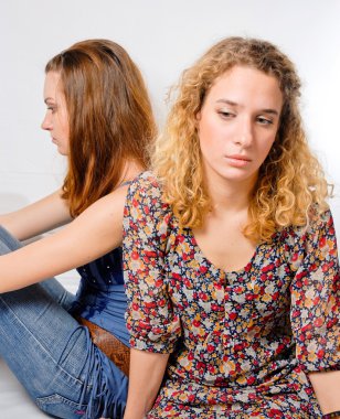 Two beautiful young women looking away & sad on white background clipart