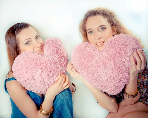 Pink hearts: Two beautiful young women with pink hearts of love on white background — Stock Photo, Image