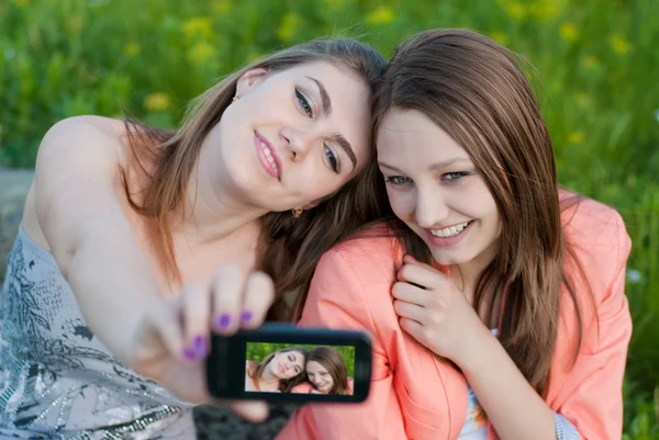 Duas adolescentes felizes tirando fotos de si mesmas com telefone celular — Fotografia de Stock