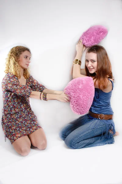 Portret van twee mooie jonge vrouwen spelen met twee roze harten op witte achtergrond — Stockfoto