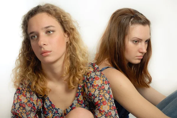 Dos hermosas mujeres jóvenes mirando hacia otro lado triste sobre fondo blanco — Foto de Stock