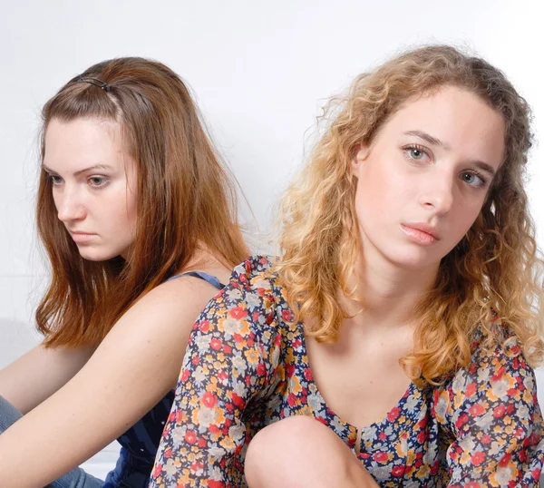 Две красивые молодые женщины, глядящие в сторону и грустные на белом фоне — стоковое фото