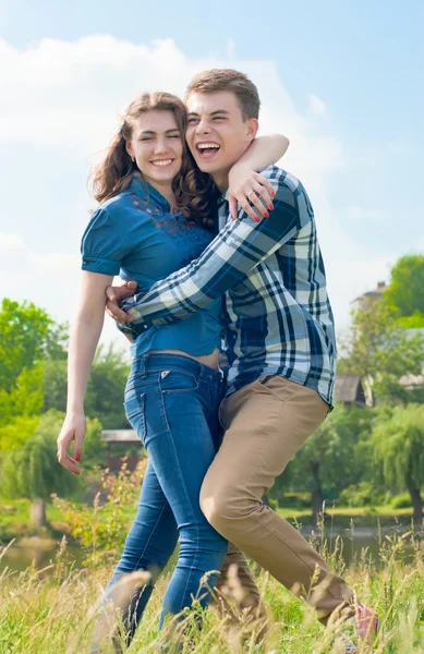 Feliz casal adolescente abraçando sobre fundo céu azul — Fotografia de Stock