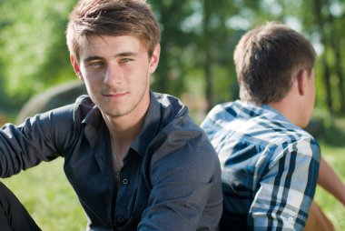 birlikte yeşil çimenlerin üzerinde oturan iki genç adam