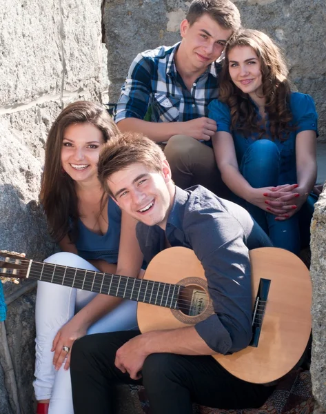 Четыре счастливых друга-подростка и гитара — стоковое фото