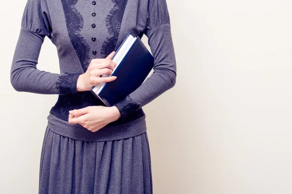 Giovane bella donna in abito grigio vintage in possesso di bibbia — Foto Stock