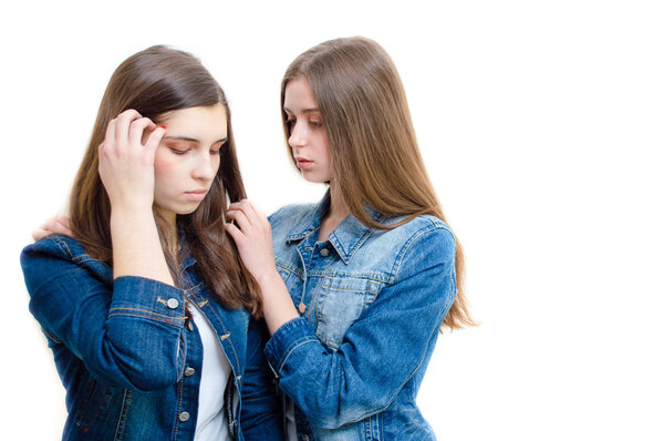 Two beautiful young women comforting one another on white background