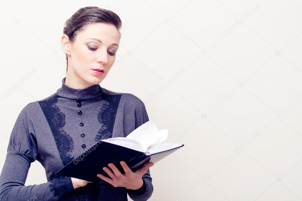 Young beautiful woman in vintage dress reading bible