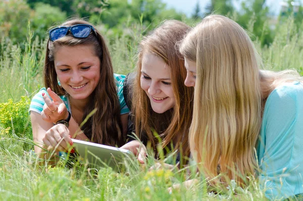 Drie gelukkige tiener meisje vrienden en tablet pc — Stockfoto