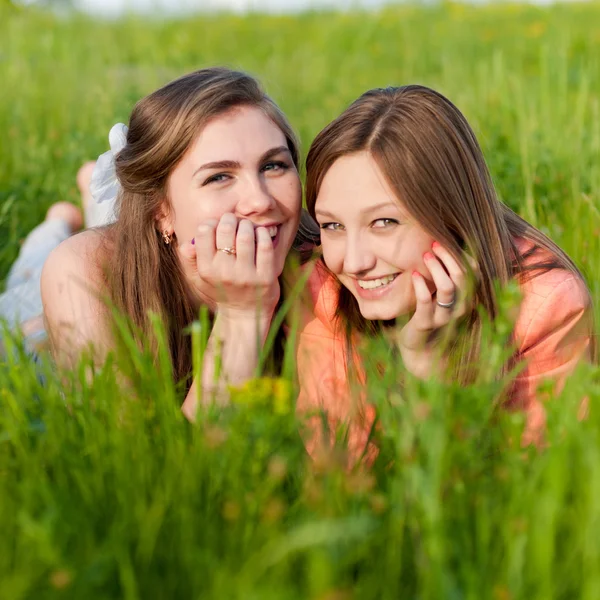Dois teen menina amigos rindo no verde grama — Fotografia de Stock