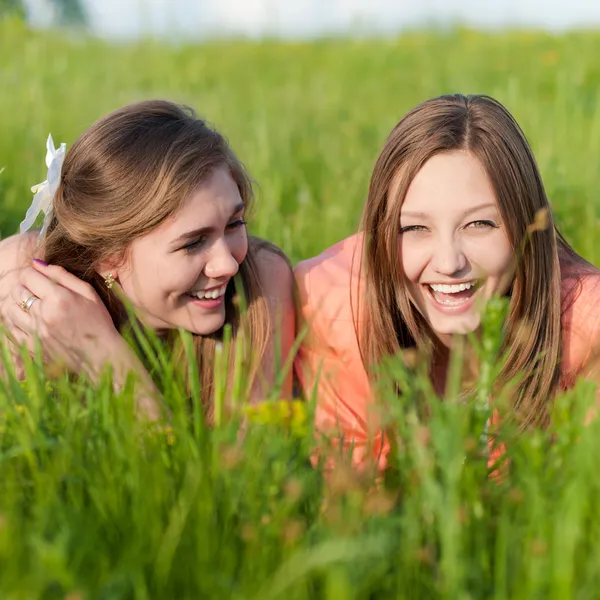 Zwei Teenie-Freundinnen lachen im grünen Gras — Stockfoto