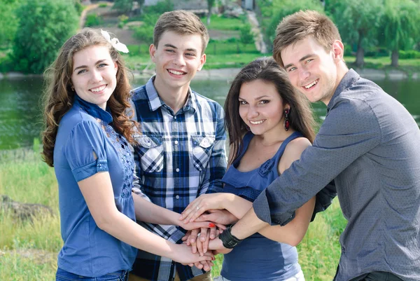 Cuatro felices amigos adolescentes tomados de la mano como equipo —  Fotos de Stock