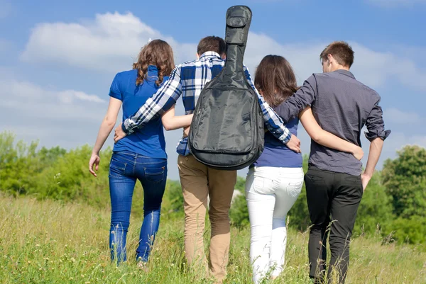 Fyra glada tonåriga vänner gå tillsammans utomhus — Stockfoto