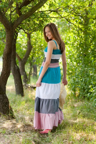 Jeune femme heureuse portant une robe longue marchant dans un parc vert — Photo