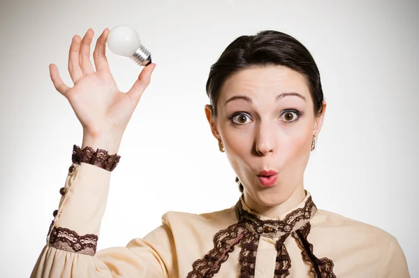 Smiling beautiful woman having an idea with light bulb over her head — Stock Photo, Image