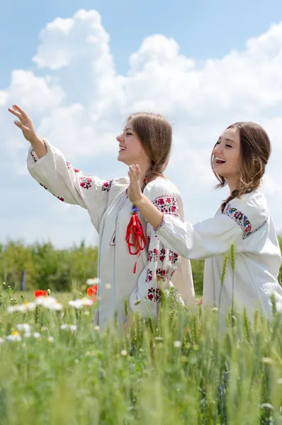 Δύο νεαρές γυναίκες χαρούμενος στην παραδοσιακή ουκρανική φόρεμα στον τομέα του σίτου — Φωτογραφία Αρχείου