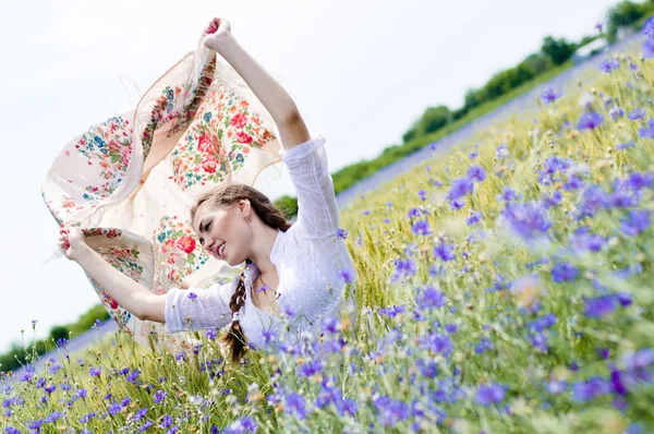 Junge lächelnde Frau steht im gelben Weizenfeld und hält ein weißes Tuch im Wind — Stockfoto