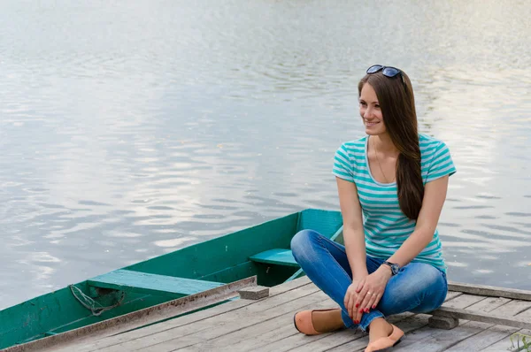 İskele üzerinde oturan ve gülümseyen genç kadın — Stok fotoğraf