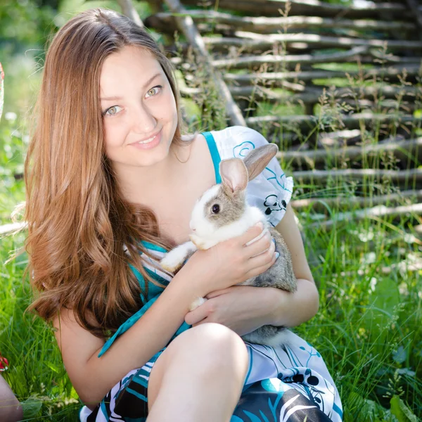 Joven mujer feliz abrazando pequeño conejo al aire libre — Foto de Stock