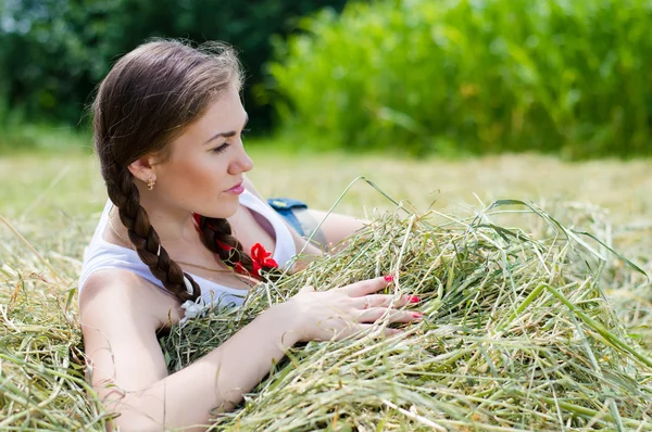 ある夏の日干し草に横たわって若い美しい女性 — ストック写真