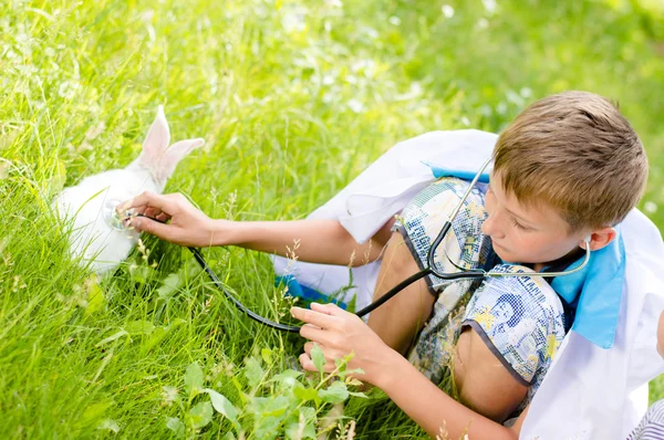 Giovane ragazzo felice prendersi cura di piccolo coniglio all'aperto — Foto Stock