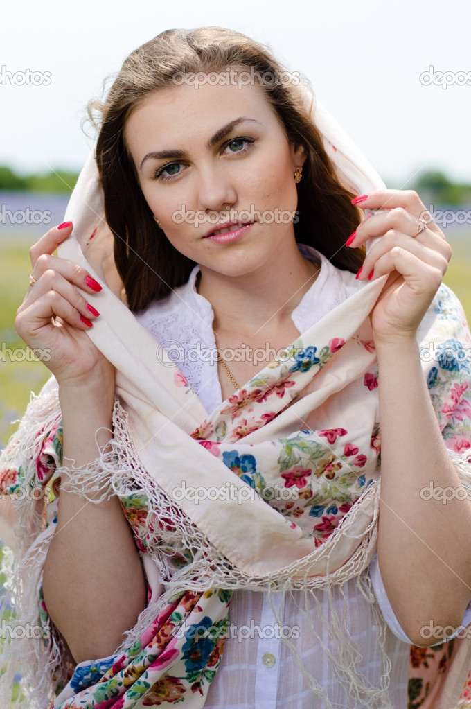 Young beautiful woman standing in yellow wheat field in shawl