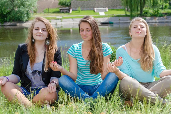Três meninas adolescentes sentadas na posição de ioga e meditando — Fotografia de Stock