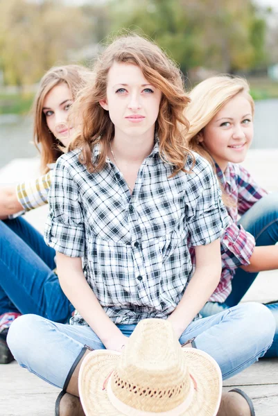 Drei glückliche Mädchen, die zusammen draußen sitzen — Stockfoto