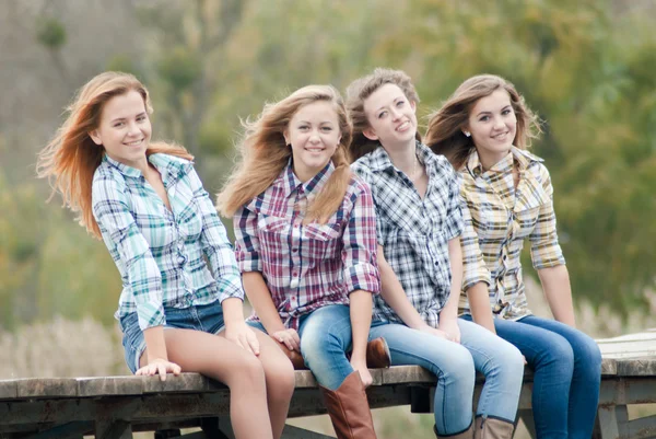 Vier meisjes zitten op rivier brug — Stockfoto