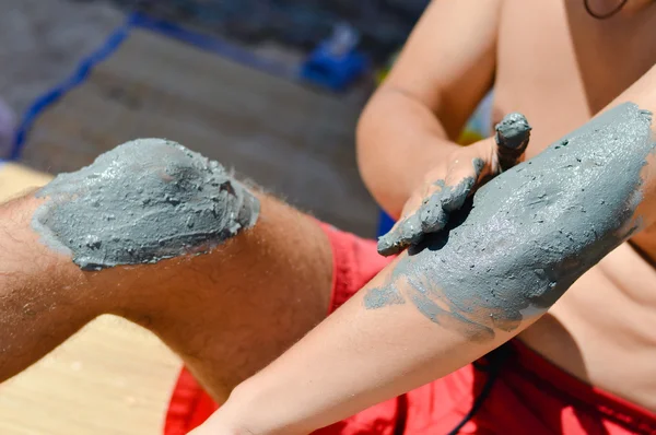 Man applying mineral blue mud on knee and elbow — Stock Photo, Image