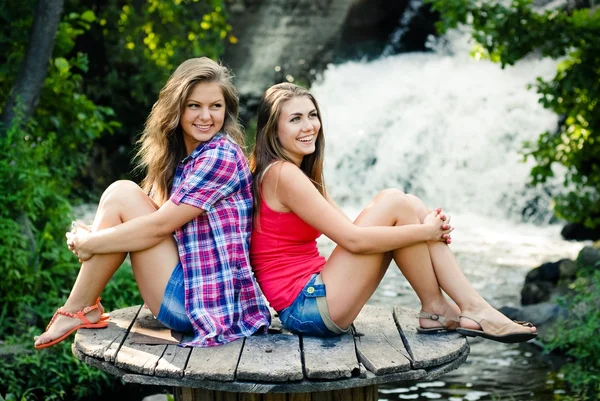 Две девочки сидят у водопада — стоковое фото