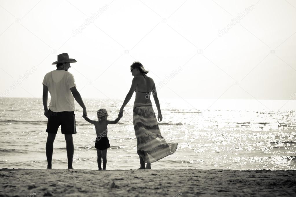 Happy family of three on sandy beach having fun