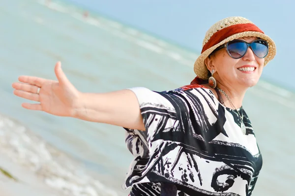 Happy mature woman enjoying breeze on seashore — Stock Photo, Image