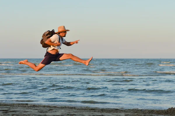 Jovem homem ativo pulando alto e correndo na praia — Fotografia de Stock