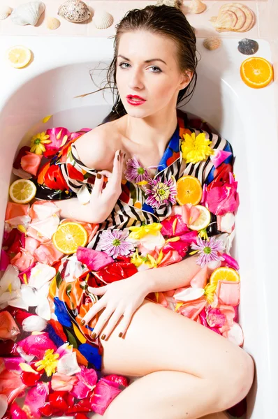 Belle jeune femme sexy dans le bain avec des fleurs et des fruits — Photo