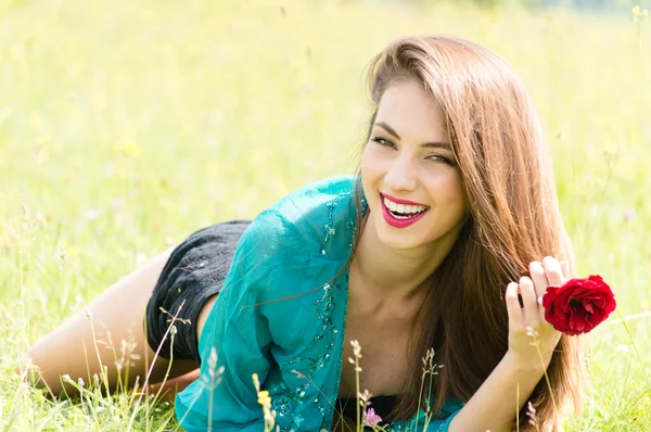 Beautiful young woman outdoors holding red rose — Stock Photo, Image