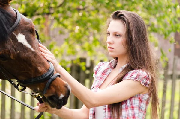Beautiful young woman holding horse on summer day — Stock Photo, Image