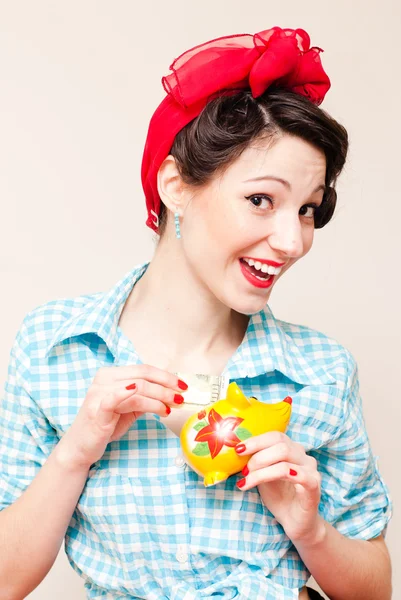 Retro pinup woman put money dollar note to porcelain mouse bank — Stock Photo, Image