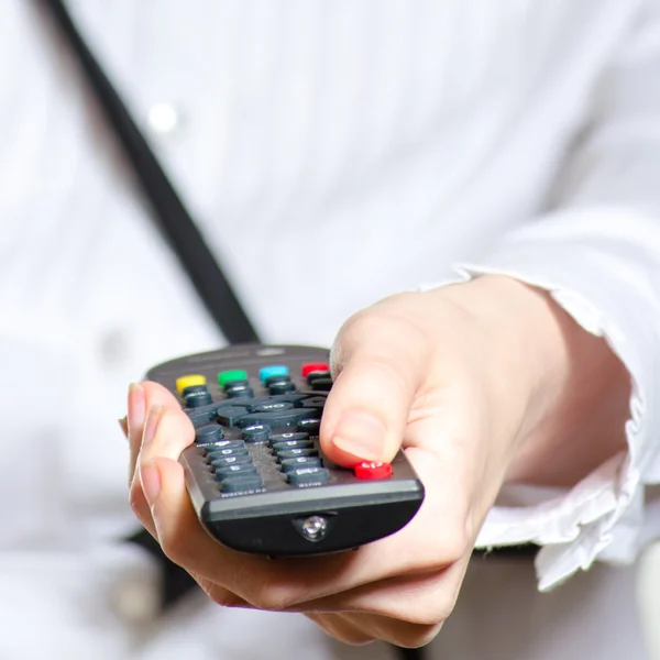 Woman holding remote control and pushing power button Stock Image