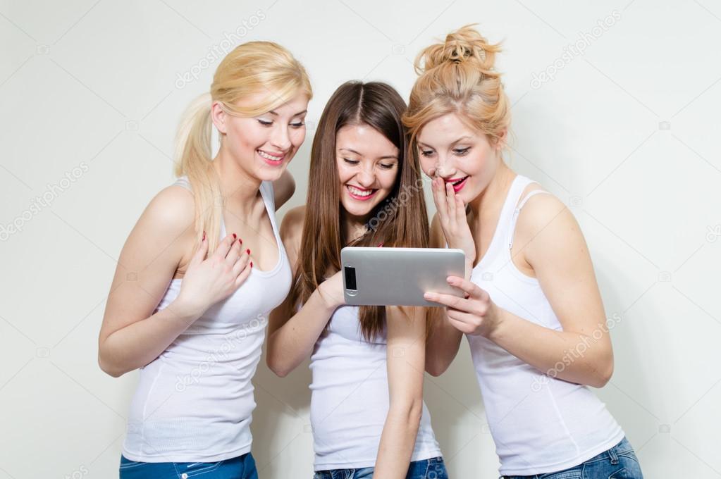 Three happy women looking on tablet and laughing