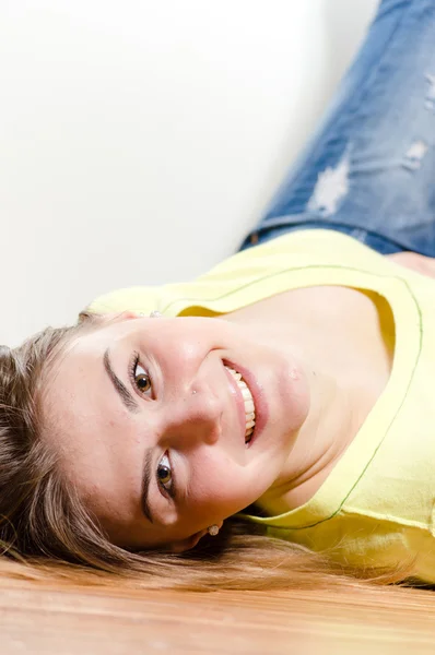 Mujer joven feliz acostada en el suelo y sonriendo alegremente — Foto de Stock