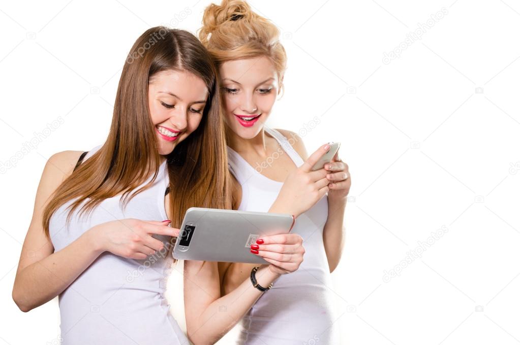 Two happy women looking on tablet pc and smiling