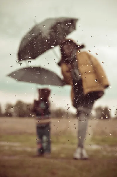 Madre e figlio sotto forma di ombrello attraverso la finestra bagnata — Foto Stock
