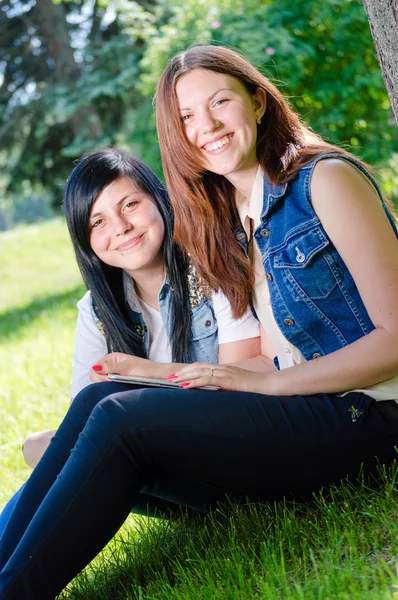 Två unga kvinnliga studenter som sitter i parken med TabletPC — Stockfoto