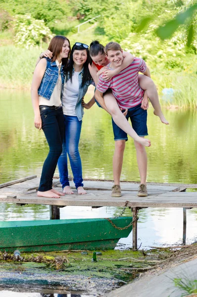 Four happy teen friends have fun on pier — Zdjęcie stockowe